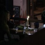 Candlelit dinner with two people talking.